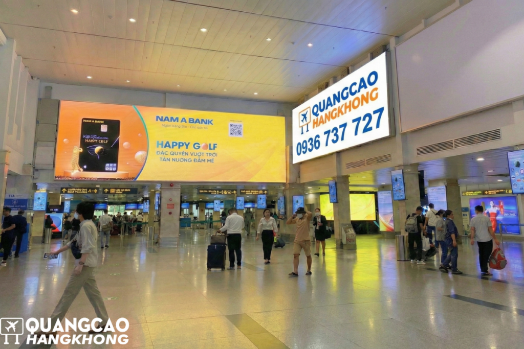 Biển hộp đèn quảng cáo đặt tại sảnh chính nhà ga sân bay với lưu lượng người qua lại đông đúc.